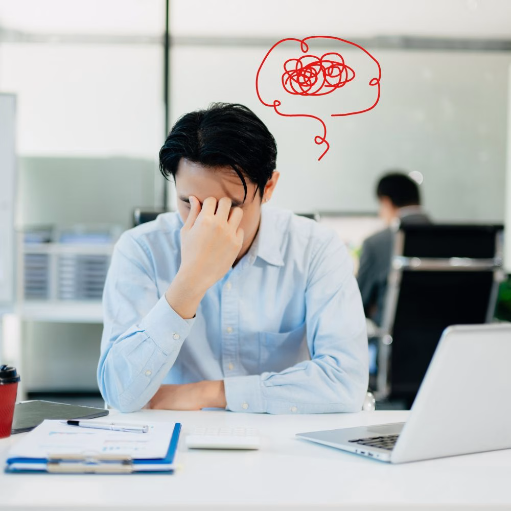 Professional feeling stressed and overthinking work tasks while practicing mindfulness techniques to improve mental wellbeing and productivity.